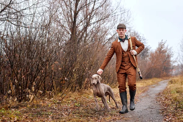 Мужчина-охотник с охотничьей собакой Ваймаранер портрет друга в сельской местности во время охоты — стоковое фото