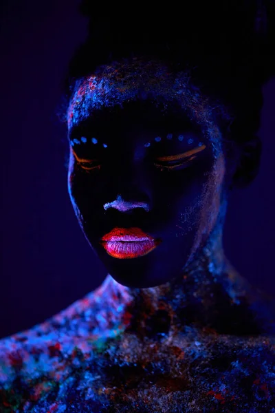 Sensual hembra con piel negra en maquillaje de pintura fluorescente, posando a cámara —  Fotos de Stock