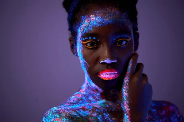 Nyugodt fekete modell nő neon fényben. fekete modell fluoreszkáló sminkkel — Stock Fotó