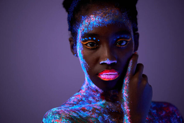 calm black model woman in neon light. black model with fluorescent make-up