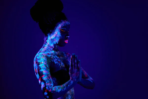 Preghiera nera con arte del corpo UV incandescente nel buio, stampe etniche colorate sulla pelle nuda — Foto Stock