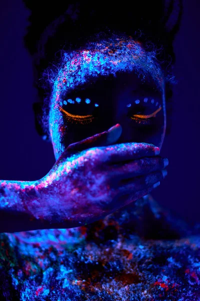 Absztrakt lövés gyönyörű fekete nő csukott száj kézzel, fluoreszkáló test művészet — Stock Fotó