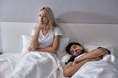 Mutsuz genç kadın ve erkek tartışmadan sonra konuşmuyorlar, evde yataktalar.