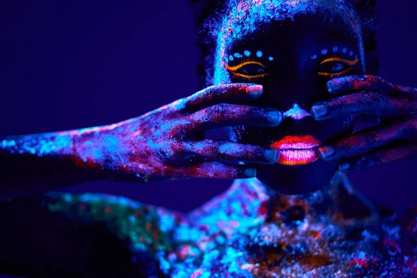 Mujer negra con impresiones fluorescentes en la piel, pintura cósmica que brilla sobre luces de neón —  Fotos de Stock