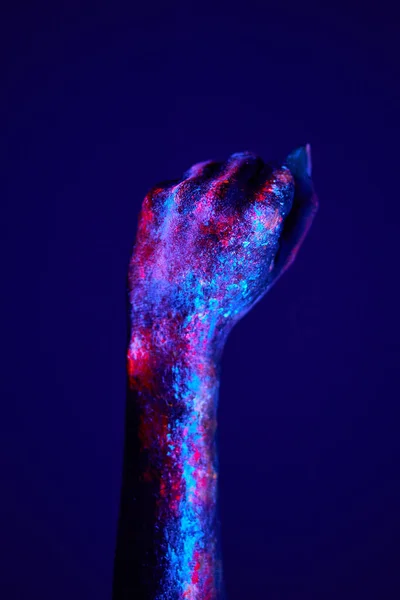 Gebalde vrouwelijke vuist hand close-up op donkerblauwe neon achtergrond conceptuele studio — Stockfoto