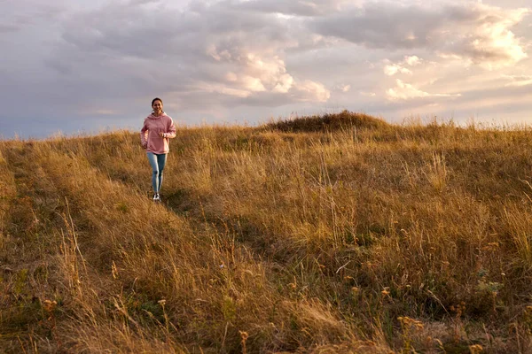 Young woman in sportswear running in field. Active rest on weekends. Traveling in nature. — Stock Photo, Image