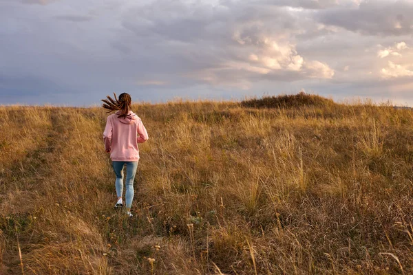 Hátsó kilátás nő fut naplementekor vagy napkeltekor mentén mezei hegyek, reggeli kocogás — Stock Fotó