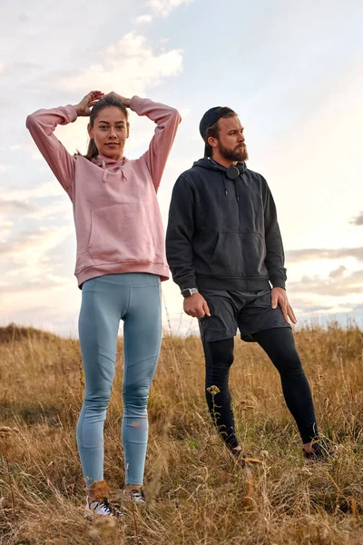 Pareja en maravilloso paisaje de campo tienen descanso después de correr, entrenamiento deportivo al aire libre — Foto de Stock