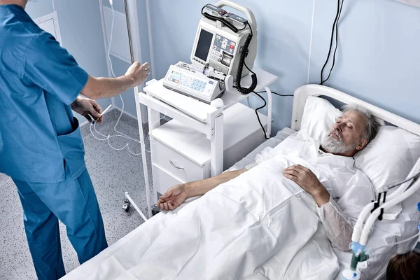 Senior man covid-19 patient ligger på sängen på sjukhus, på isoleringsenhet på sjukhus — Stockfoto