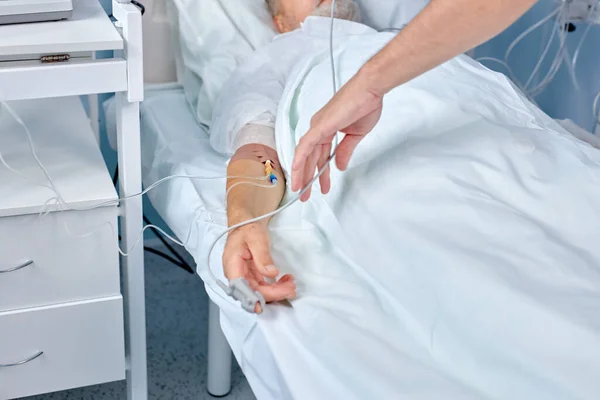 Primo piano dell "uomo mano con siringa in vena. Persona sdraiata in cliniche letto con catetere. — Foto Stock
