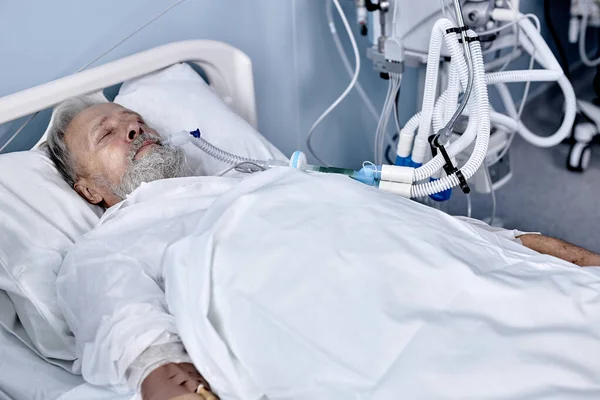 Malato paziente caucasico maturo sdraiato sul letto in ospedale, flebo endovenoso salino a portata di mano — Foto Stock