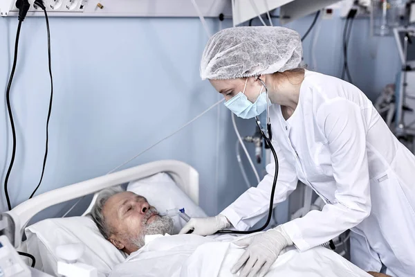 Paciente masculino de edad avanzada que recibe consulta del médico utilizando estetoscopio para el examen de latidos cardíacos — Foto de Stock