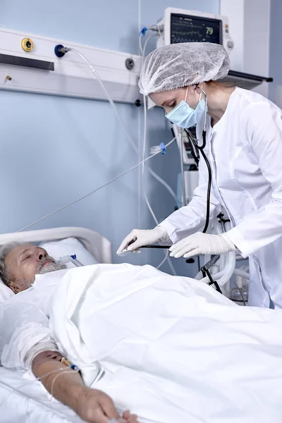 Paciente masculino de edad avanzada que recibe consulta del médico utilizando estetoscopio para el examen de latidos cardíacos —  Fotos de Stock