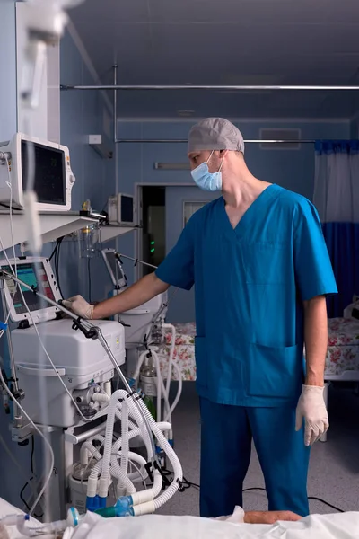 Manlig läkare som står vid medicinsk utrustning och kontrollerar patientens hjärtslag — Stockfoto