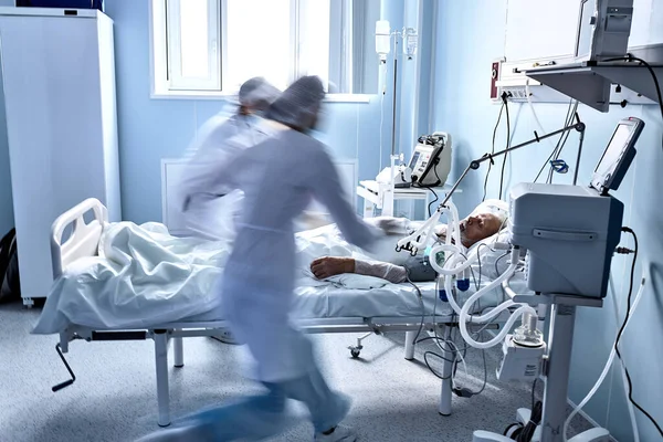 doctors run around the ward trying to help dying patient, lying on bed in hospital