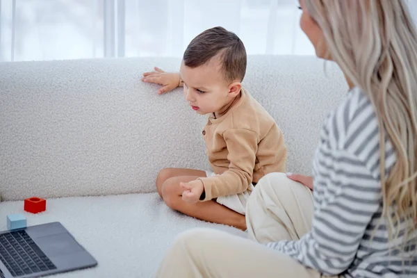 Ritagliato madre e bambino seduto sul divano a casa guarda il video sul computer portatile moderno — Foto Stock