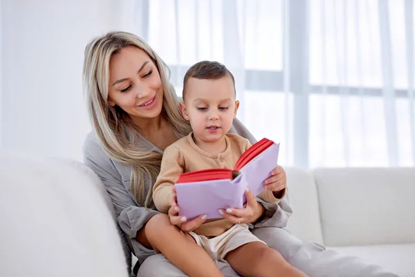 Glücklicher kaukasischer kleiner Junge hört Mutter zu, liest lustige Geschichten oder Märchen. — Stockfoto