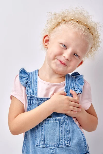 Bonito feliz menina pequena isolado no estúdio branco fundo segurar as mãos no peito do coração — Fotografia de Stock