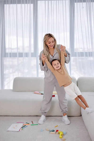 La madre positiva se divierte con el hijo en la acogedora sala de estar de luz, criar a un niño —  Fotos de Stock