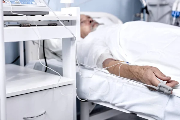 Primo piano della mano maschile con siringa in vena. Persona sdraiata in cliniche letto con catetere. — Foto Stock