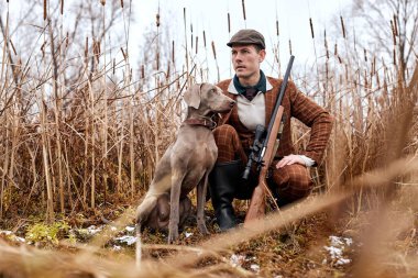 Genç avcı sonbaharda, doğada ördek avlar. Dost canlısı köpek avlanmasına yardım et.