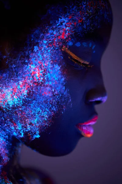 Kroppskonst glöder i ultraviolett ljus, närbild ansikte svart kvinna med stora läppar — Stockfoto
