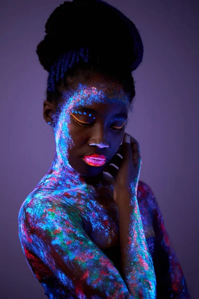 Schwarze Frau mit Körperkunst in UV-Licht. Frau mit fluoreszierendem Pulver bemalt — Stockfoto