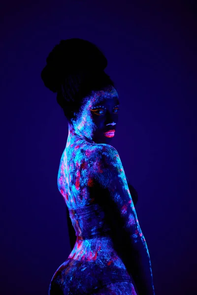 Szczupła czarna kobieta z luminescencją, fluorescencją, body art wyizolowana po ciemku — Zdjęcie stockowe