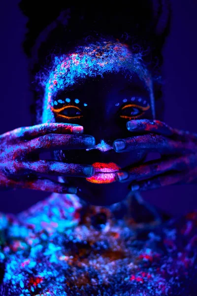Junge schwarze Hündin mit fluoreszierenden Abdrücken im Gesicht, ungewöhnlichen Abdrücken, Body Art — Stockfoto