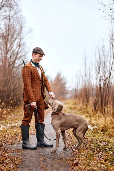 初秋の風景の中に美しい強い犬のWeimaraner品種とハンター男 — ストック写真