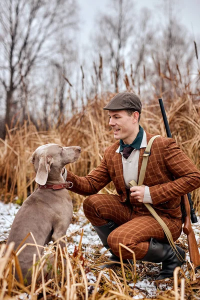 Heyecanlı adam av tüfeğini tutar ve köpeği okşar, ormanda, avlanmaya gelir.. — Stok fotoğraf