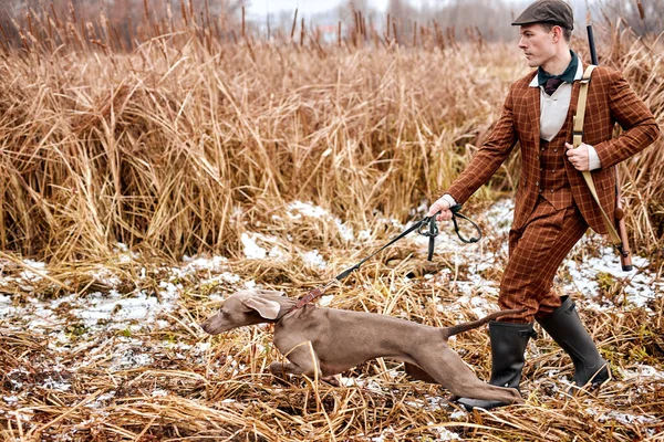 Perro cazador lleva al hombre cazador a un lado, dirige. naturaleza rural, lugar rural — Foto de Stock