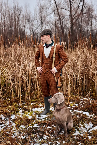 Poacher with dog in Forest. Man holding shotgun. Hunter man. Hunting period, autumn season.