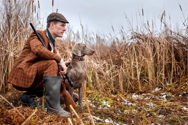 Caçador masculino em roupas de terno pronto para caçar, segurando espingarda e andando na floresta. caça — Fotografia de Stock