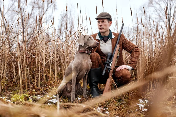 Genç avcı sonbaharda, doğada ördek avlar. Dost canlısı köpek avlanmasına yardım et.