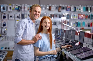 Elektronik mağazasının bilgisayar bölümündeki en iyi dizüstü bilgisayarı arayan iki alıcı.