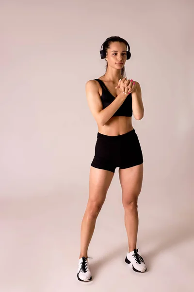 Retrato de cuerpo entero de una esbelta mujer caucásica en pantalones cortos negros y ejercicios de top doing — Foto de Stock