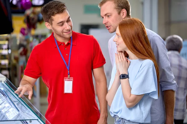 Freundlicher junger Berater hilft Kunden im Geschäft, die Wahl zu treffen — Stockfoto