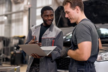 Otomobil servisinde çalışırken arabaları inceleyen çok çeşitli mekanikler.