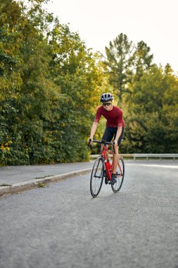 Spor bisikletli bir adam asfalt yolda bisiklet sürüyor..