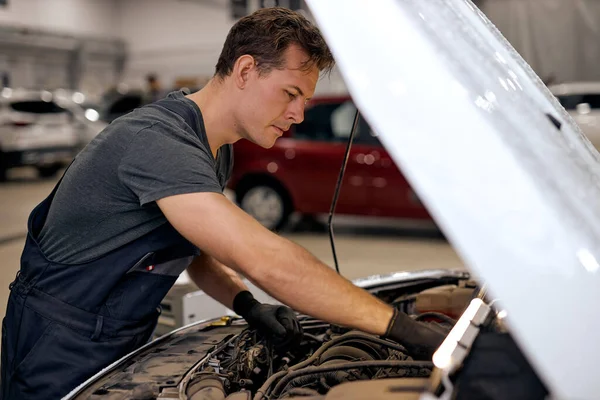 Automechanik hledající uvnitř motoru v garáži. Oprava automobilových motorů. Problémy a řešení — Stock fotografie