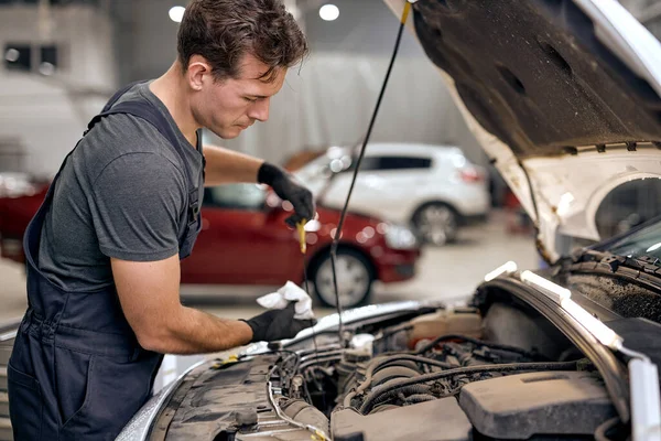 Meccanico caucasico che fa servizio auto e manutenzione. Cambio filtro olio e carburante. — Foto Stock