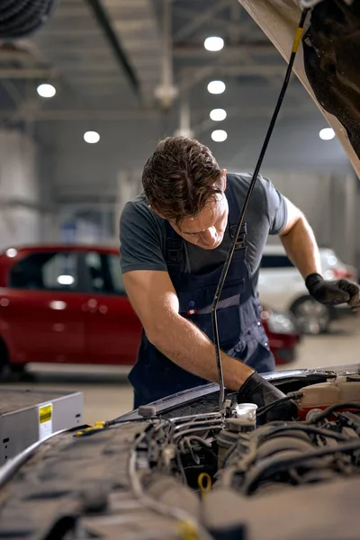 Soustředěný automechanik samec pracující sám opravuje motor auta v kapotě — Stock fotografie