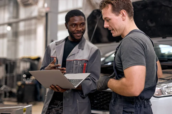 Hezké rozmanité mechaniky v uniformě zkoumání auta při práci v autoservisu — Stock fotografie