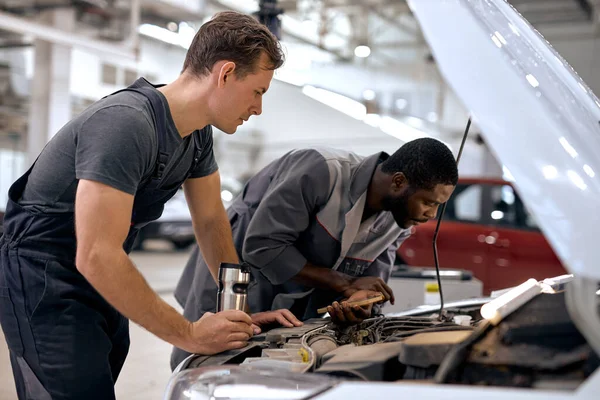 Equipo de hombres de inspección mecánica de errores de comprobación en el motor desde el teléfono inteligente aplicación. — Foto de Stock
