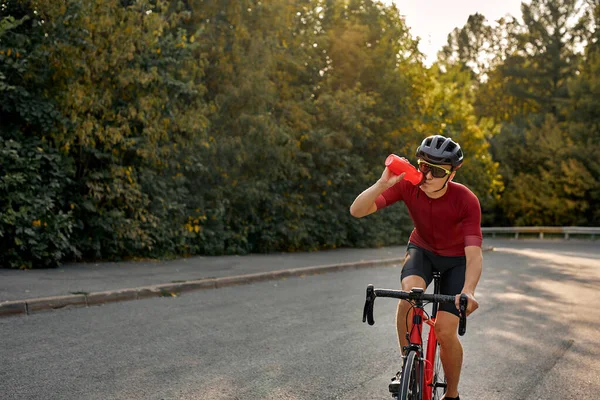 Подходит велосипедист в черном шлеме и активный износ динамично езда на велосипеде питьевой воды — стоковое фото
