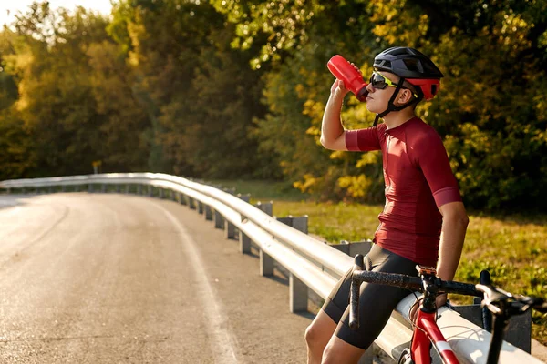 Велосипедист человек питьевой воды во время отдыха после интенсивного вождения велосипеда, веселый велосипедист — стоковое фото