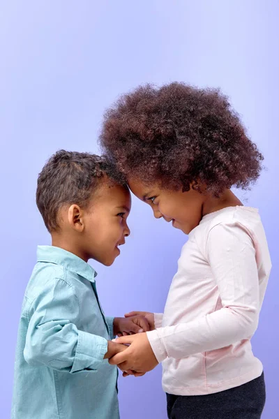两个可爱的小朋友抱在一起手挽手 彼此隔离在紫色的彩色背景下 可爱的小男孩和穿着休闲装的小女孩快乐地摆姿势 — 图库照片