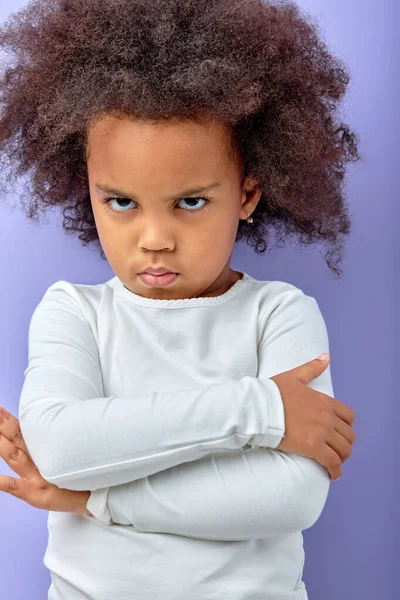 被紫色背景隔离的 抱着胳膊的不高兴的 生气的小女孩 被激怒的黑人小孩 双臂交叉在相机前摆出姿势 满脸怒容 儿童与人类情感 — 图库照片