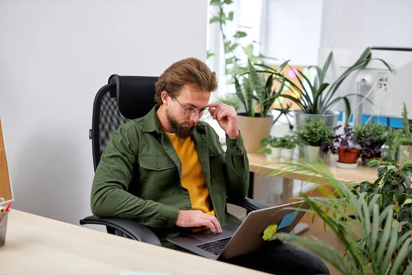 concentrated serious man sit with laptop thinking having brainstorm, working hard, in bright office. manager guy with beard focused on work. at workplace. people lifestyle, job concept